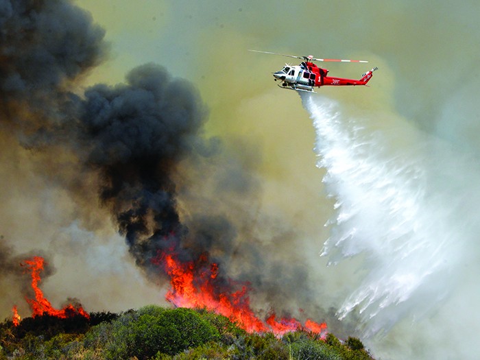A Los Angeles City Fire helicopter drops water on flames, Wednesday, June 24, 2015, in Santa Clarita, Calif. About 1,000 people have been evacuated from homes as a 100-acre wildfire burns through brushy canyonlands north of Los Angeles. (AP Photo/Rick McClure)